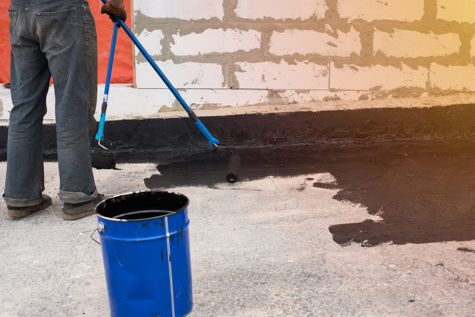 A worker sealing a basement floor | Buying a house with a basement